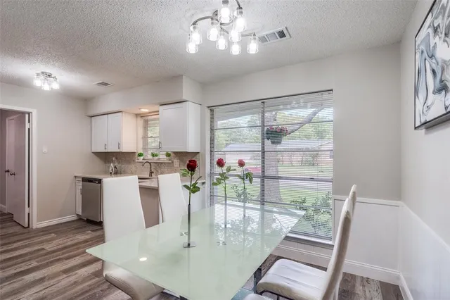 a dining room with wooden floor a chandelier a glass table and chairs