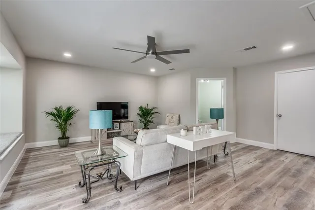 a living room with furniture a potted plant and a ceiling fan