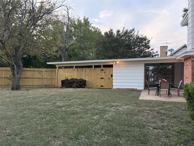 a view of a backyard with table and chairs and wooden fence