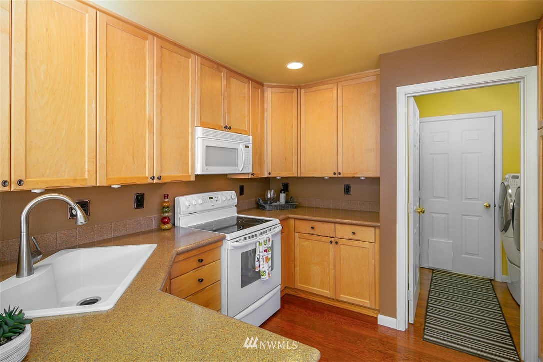 19133 110th Place Southeast Renton, WA 98055 - Photo 7 of 17 a kitchen with stainless steel appliances granite countertop a sink a stove and white cabinets with wooden floor