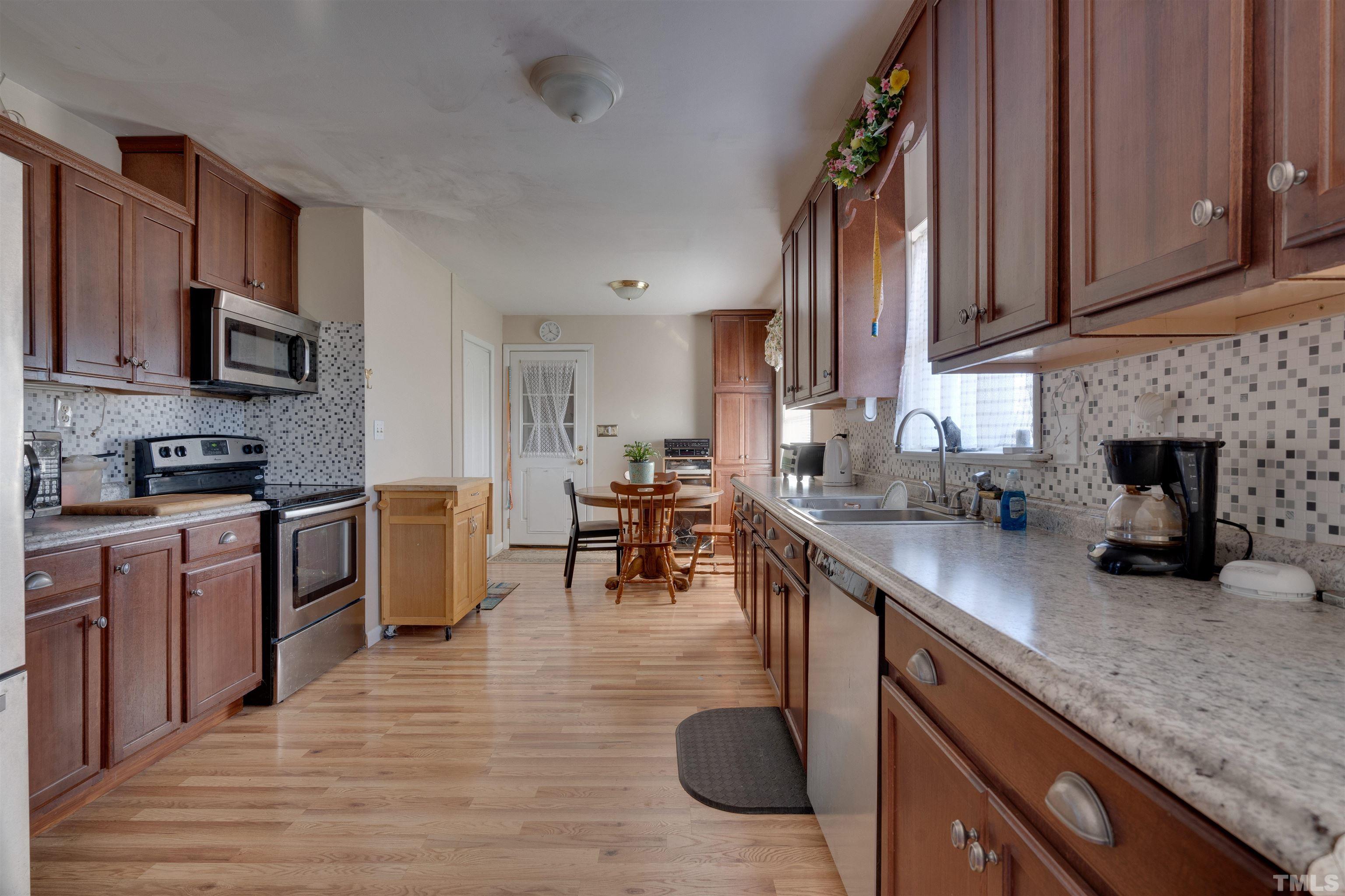 245 Pilot-Riley Road Zebulon, NC 27597 - Photo 13 of 22 a kitchen with stainless steel appliances granite countertop a stove top oven a sink a dining table and chairs with wooden floor