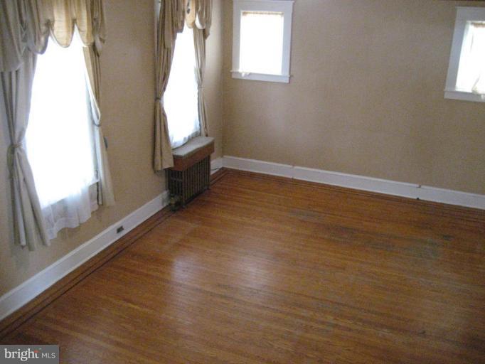 503 Westgate Road Baltimore, MD 21229 - Photo 3 of 24 an empty room with wooden floor and windows
