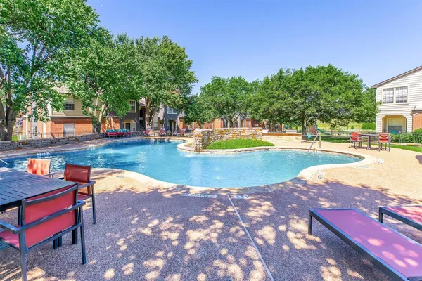 a view of swimming pool with lawn chairs and plants