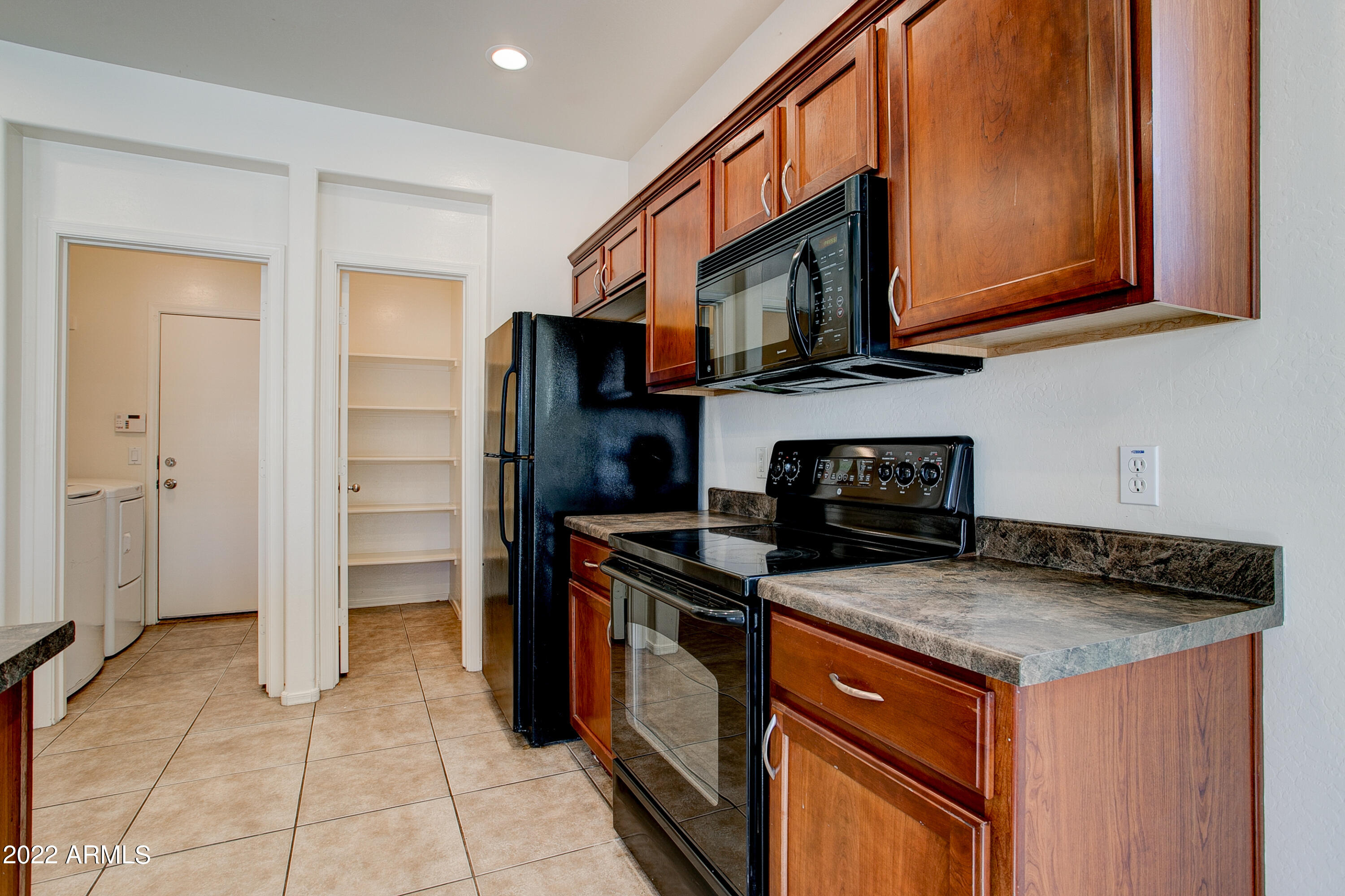 9928 West Chipman Road Tolleson, AZ 85353 - Photo 12 of 42 a kitchen with stainless steel appliances granite countertop a stove microwave refrigerator and sink