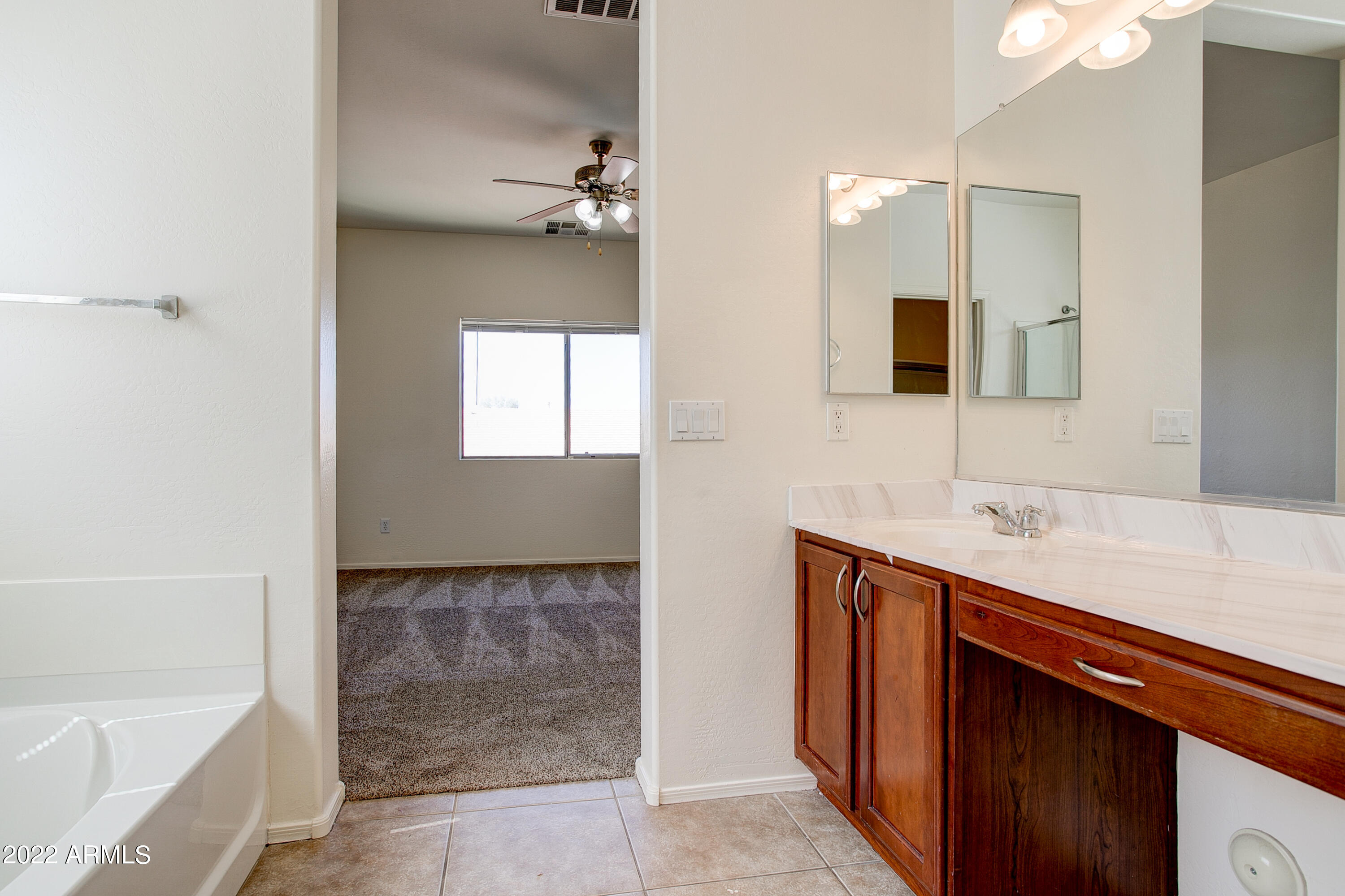 9928 West Chipman Road Tolleson, AZ 85353 - Photo 28 of 42 a bathroom with a sink a large mirror and a bathtub