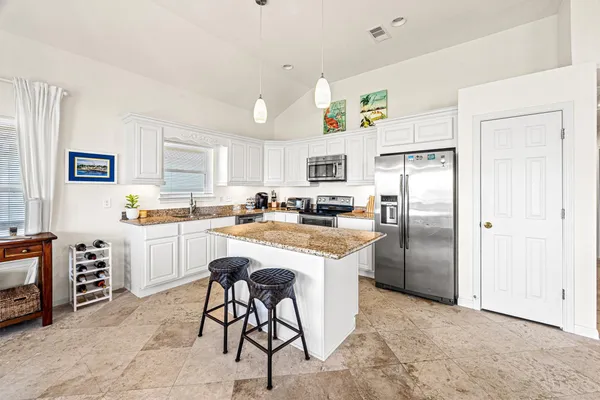 a kitchen with stainless steel appliances granite countertop a refrigerator a stove a sink a dining table and chairs with wooden floor