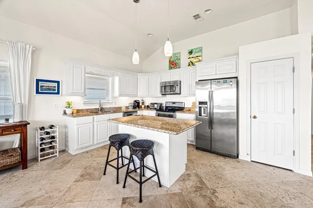 a kitchen with stainless steel appliances granite countertop a refrigerator a stove a sink a dining table and chairs with wooden floor