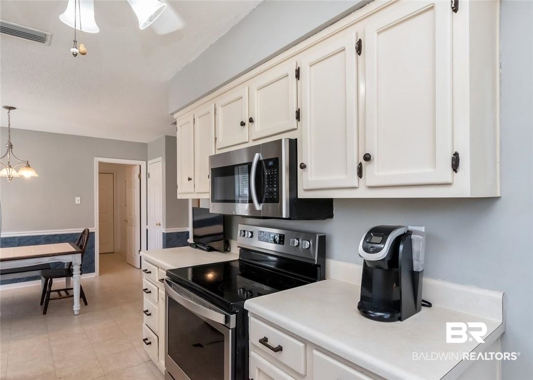 6601 Conde Court Mobile, AL 36695 - Photo 11 of 30 Kitchen with decorative light fixtures, white cabinetry, appliances with stainless steel finishes, and a notable chandelier