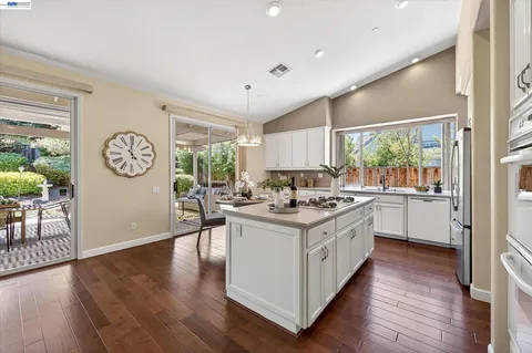 a kitchen with kitchen island granite countertop white cabinets and window