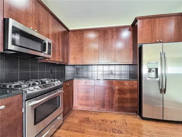 a kitchen with granite countertop a stove microwave and refrigerator