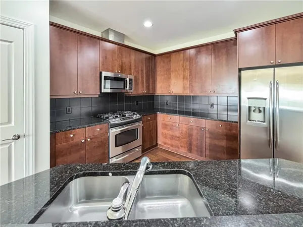 a kitchen with granite countertop a refrigerator stove and sink
