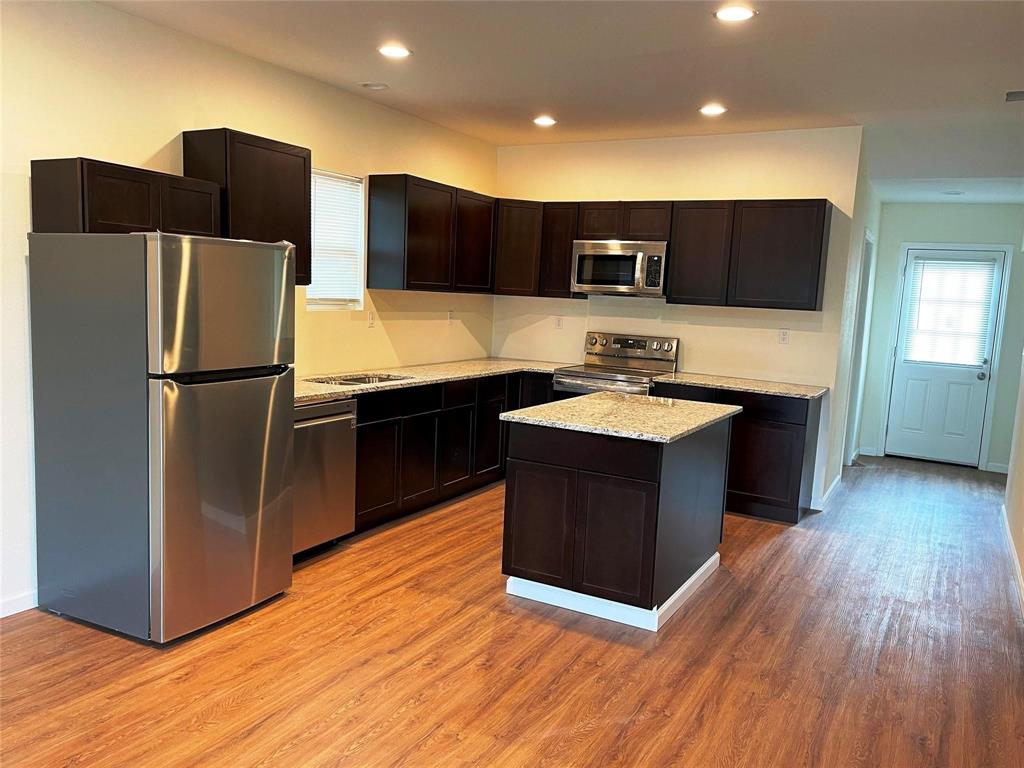 5424 Cottey Street Fort Worth, TX 76105 - Photo 3 of 8 a kitchen with stainless steel appliances granite countertop a sink and a refrigerator