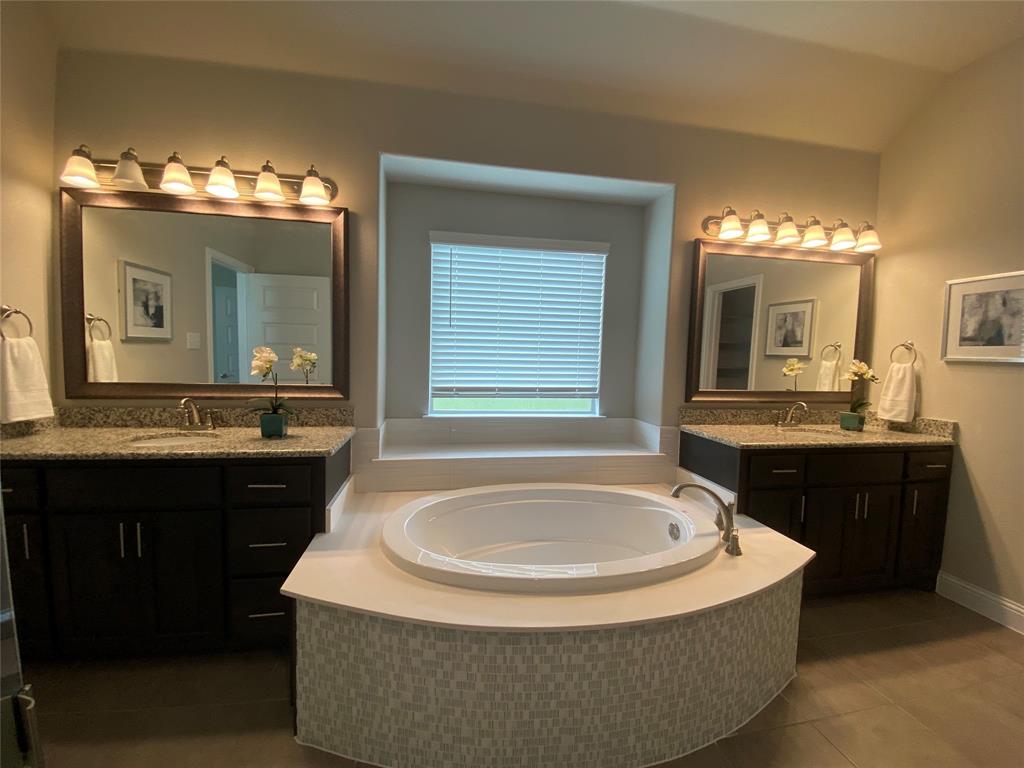 209 Johnson Street Granbury, TX 76048 - Photo 26 of 40 Bathroom with tile floors, tiled tub, dual vanity, and vaulted ceiling