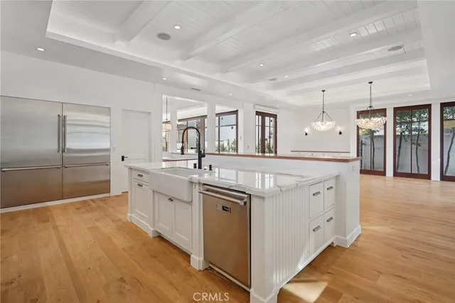 a large white kitchen with a large counter top and stainless steel appliances