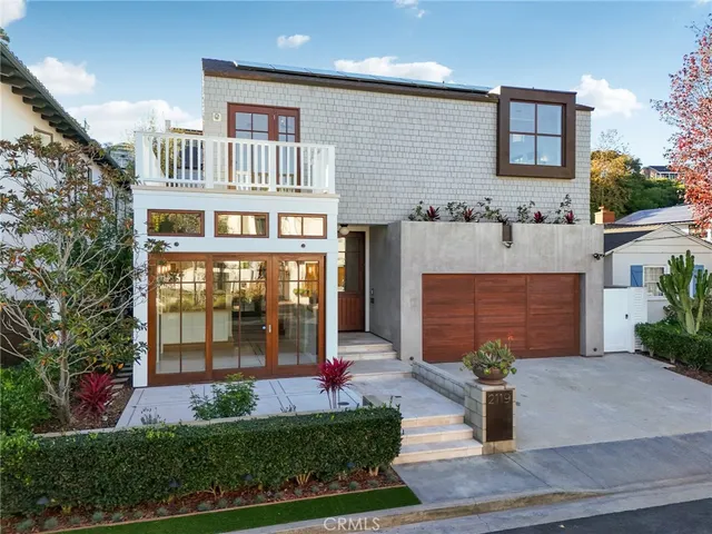a front view of a house with a yard and potted plants