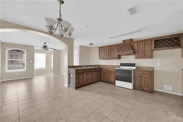 a large kitchen with a stove a sink dishwasher a kitchen island with wooden cabinets and floor