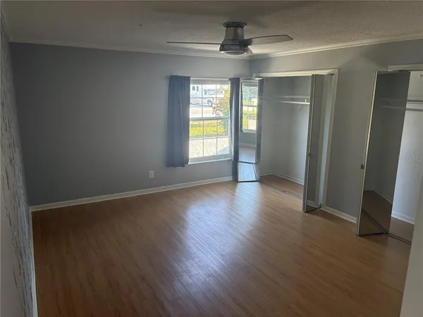 an empty room with wooden floor and windows