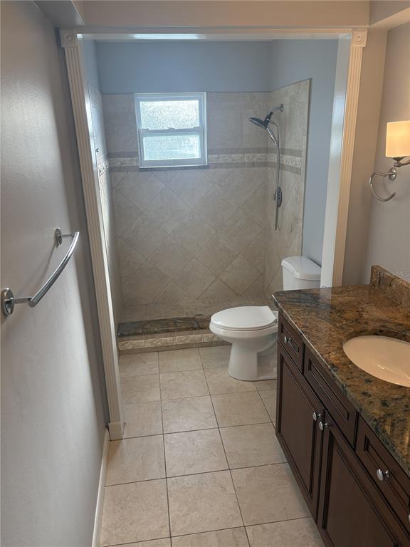 Undisclosed Address St. Petersburg, FL 33708 - Photo 3 of 11 a bathroom with a granite countertop sink a toilet a mirror and a shower