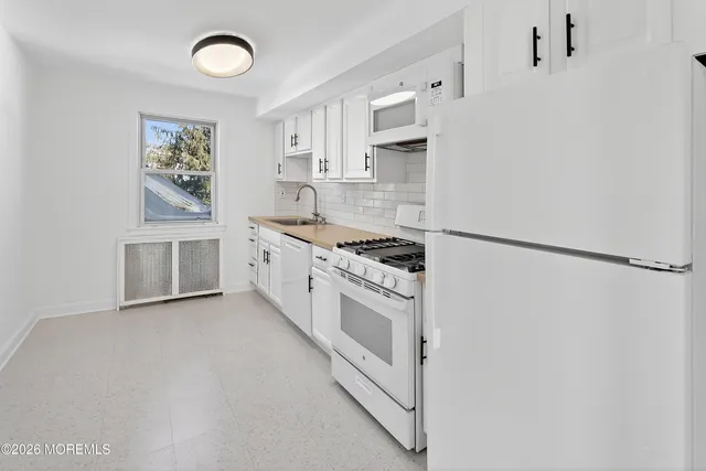 a kitchen with stainless steel appliances granite countertop white cabinets and window