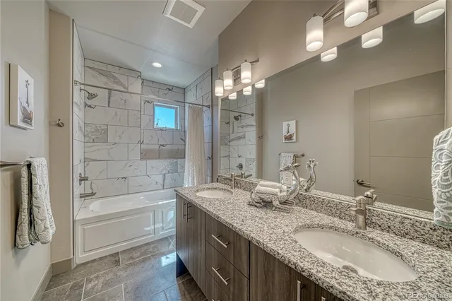 a bathroom with a granite countertop double vanity sink a mirror and a shower
