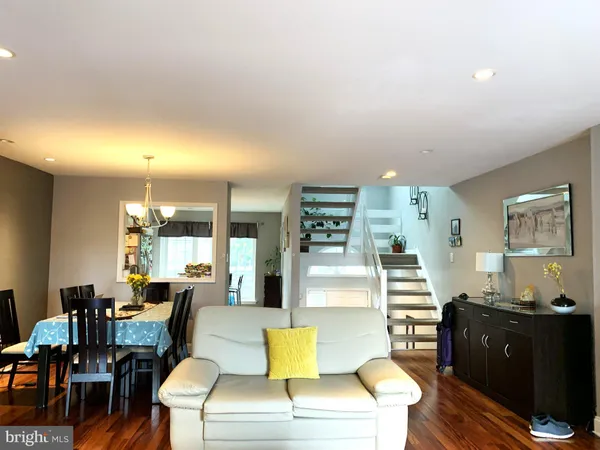 a living room with couches and kitchen view with wooden floor