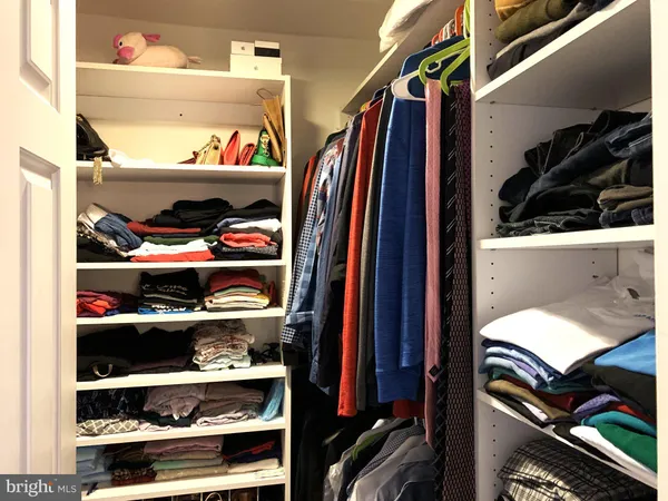 a view of walk in closet with clothes and shoes