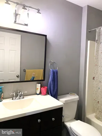 a bathroom with a toilet sink vanity and mirror