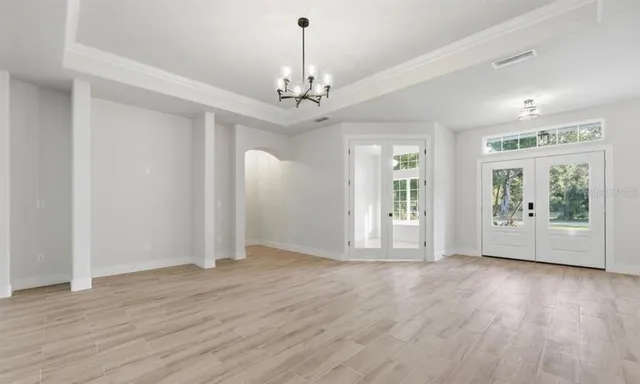 a view of an empty room with a window and chandelier fan