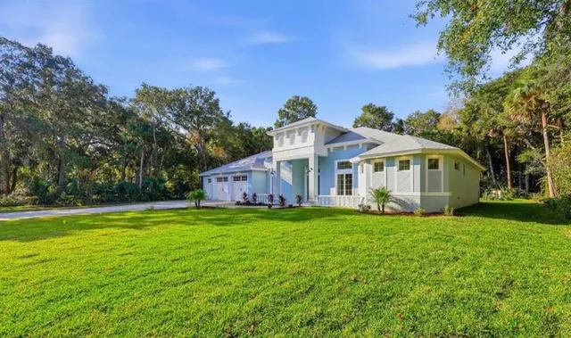 a white house with a big yard and large trees