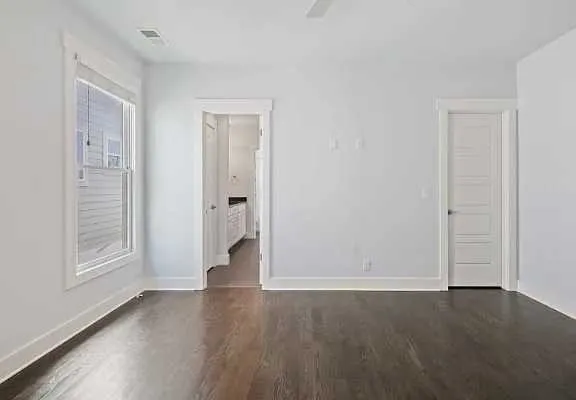 a view of an empty room with wooden floor and a window