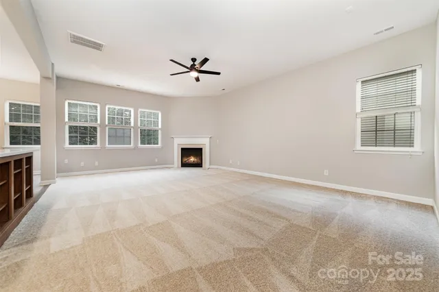 a view of an empty room with a window and kitchen view