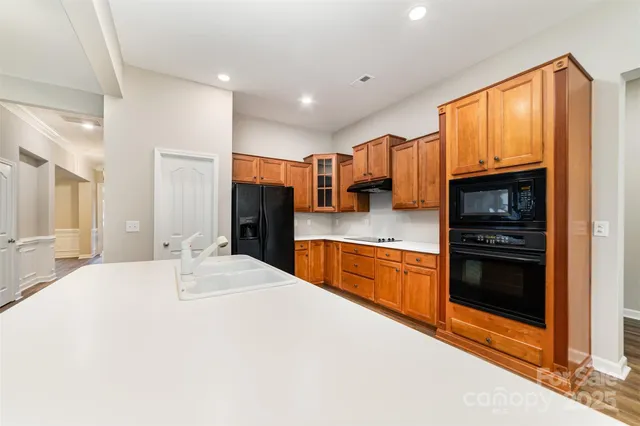 a large kitchen with stainless steel appliances kitchen island granite countertop a refrigerator and a stove top oven