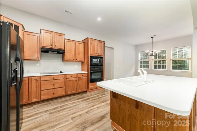 a kitchen with stainless steel appliances kitchen island granite countertop a refrigerator and a stove top oven