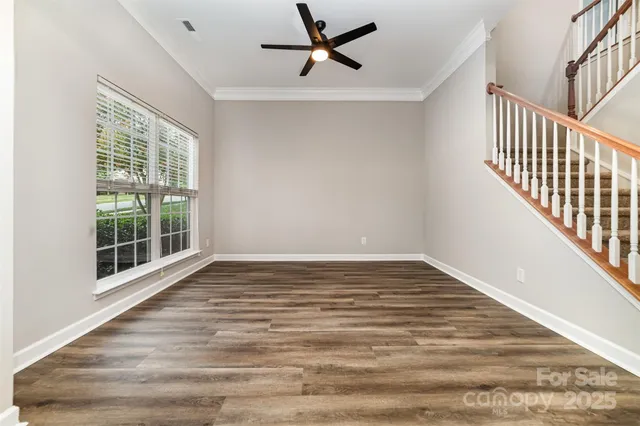 a view of empty room with wooden floor and fan