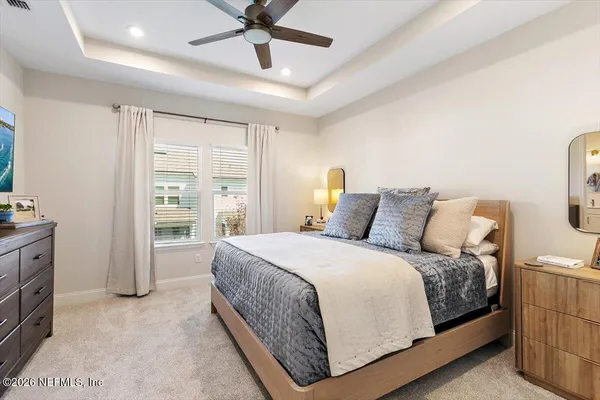a spacious bedroom with a bed a dresser and a chandelier