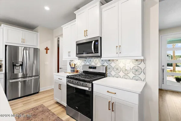 a kitchen with stainless steel appliances white cabinets and a stove top oven