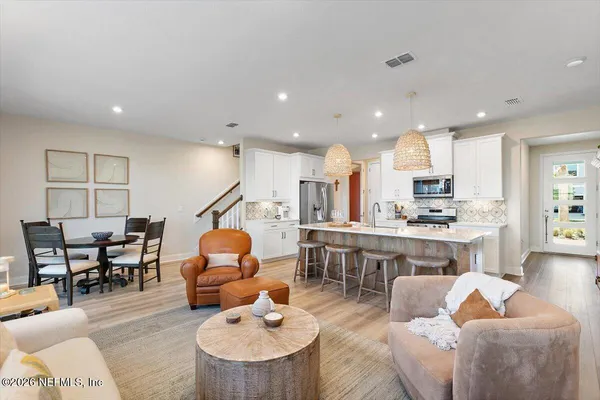 a living room with furniture kitchen view and a wooden floor