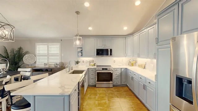 a kitchen with stainless steel appliances a stove a sink a microwave a refrigerator and white cabinets