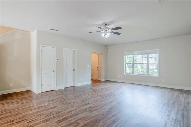 a view of empty room with wooden floor and fan