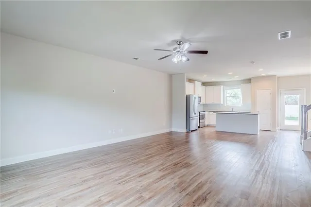 a view of an empty room with a kitchen and wooden floor