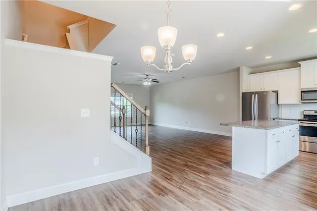 an open kitchen with wooden floor and stainless steel appliances