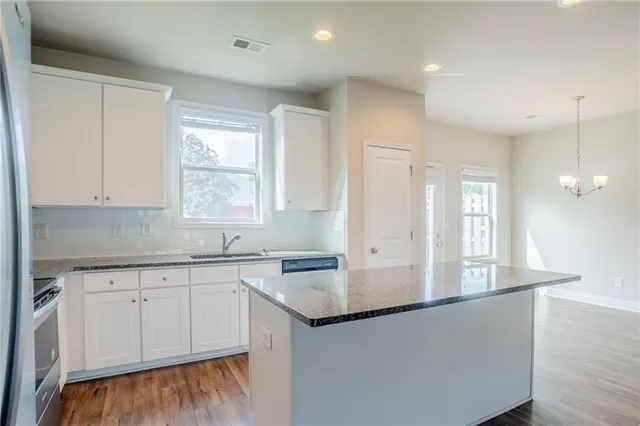 a kitchen with stainless steel appliances granite countertop a sink a stove and white cabinets