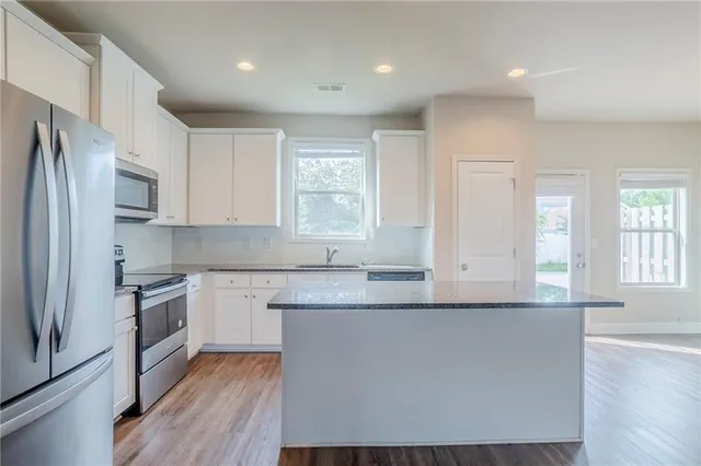 a kitchen with stainless steel appliances granite countertop a stove a sink and a refrigerator