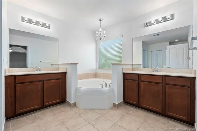 a bathroom with a tub double vanity sink and mirrors