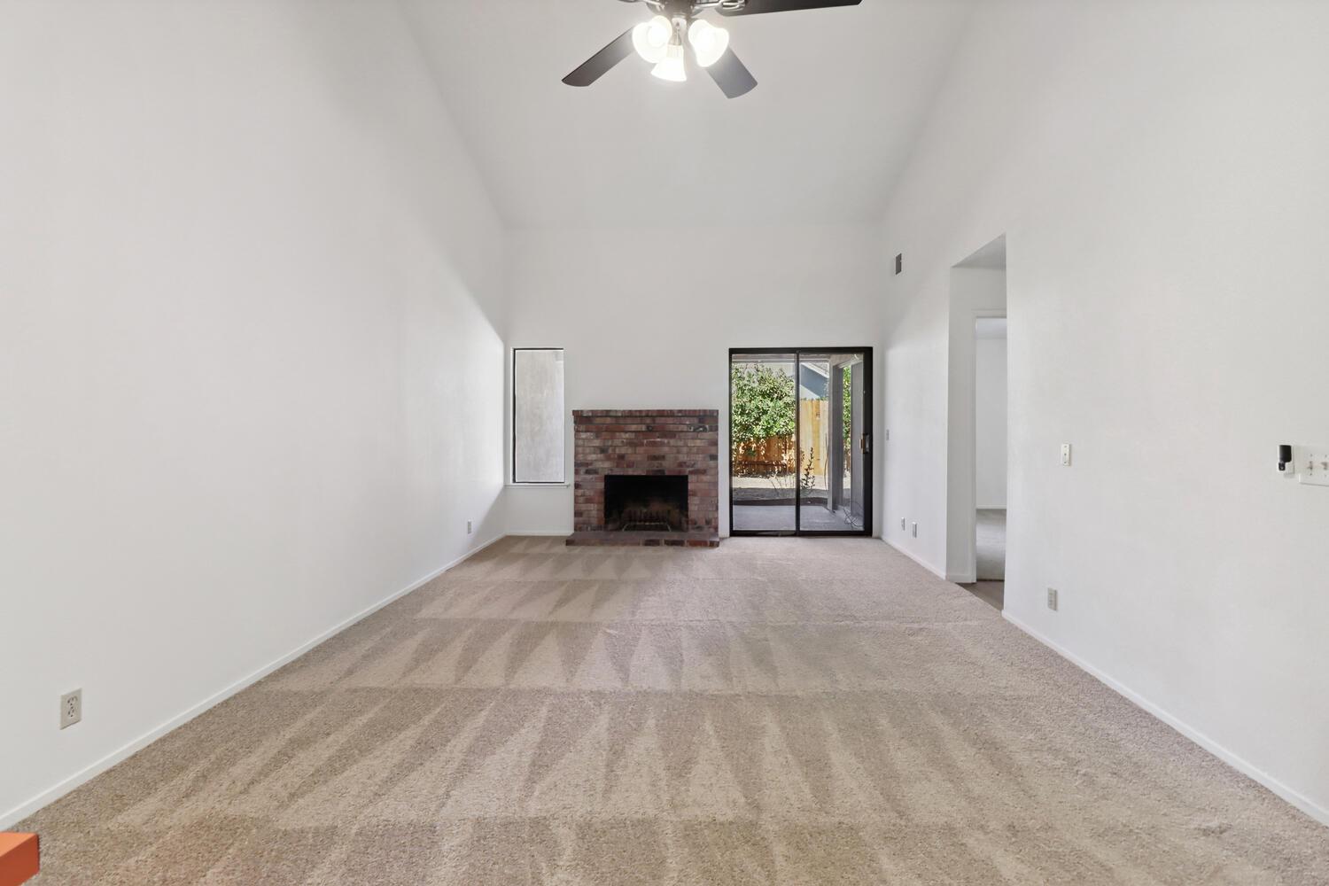 1213 Arthur Street Davis, CA 95616 - Photo 7 of 42 an empty room with fireplace chandelier fan and windows