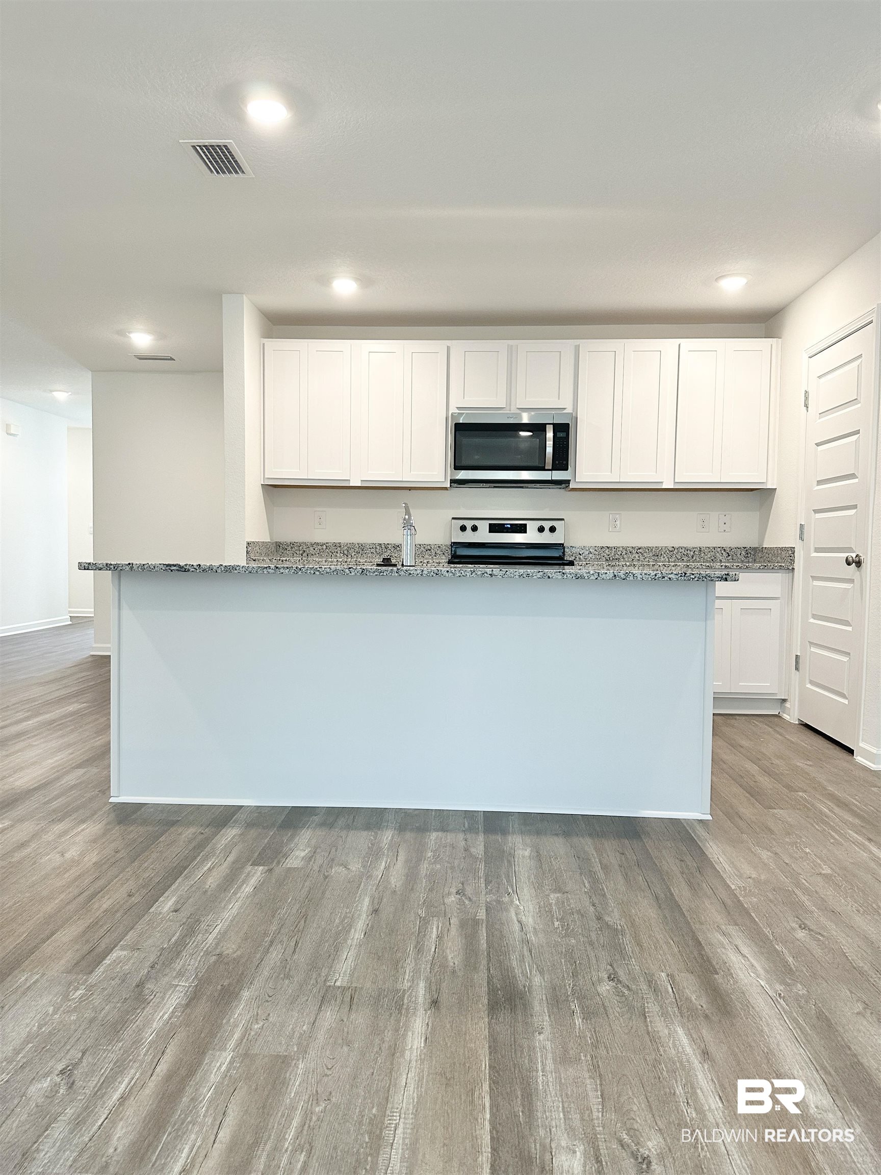 22275 Aleutian Avenue Foley, AL 36535 - Photo 6 of 72 Kitchen with white cabinetry, light stone countertops, light hardwood / wood-style flooring, and appliances with stainless steel finishes