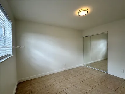 an empty room with a fan & a window