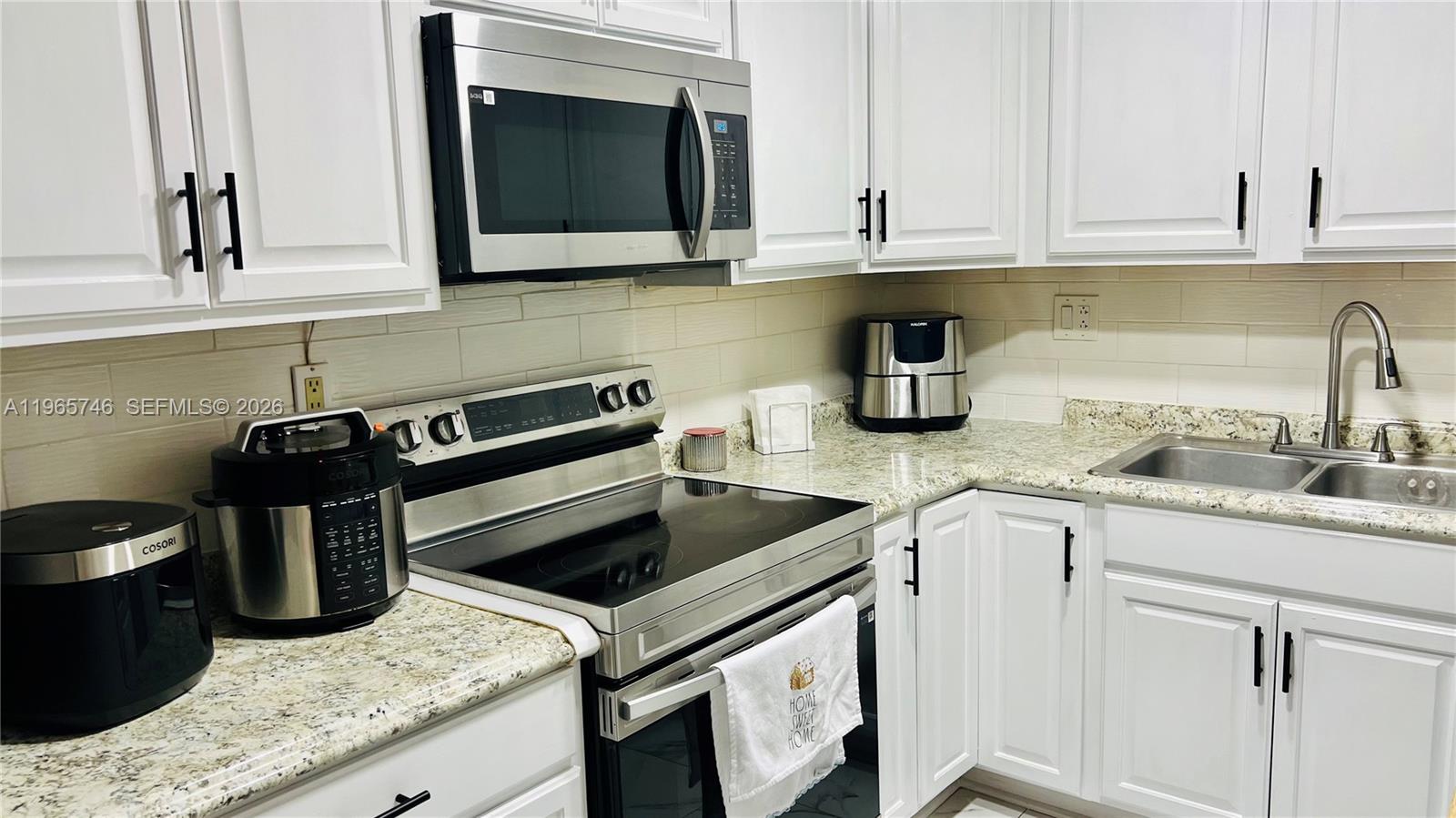 14250 Southwest 62nd Street, Unit 319 Miami, FL 33183 - Photo 7 of 29 a kitchen with granite countertop a sink stove and cabinets