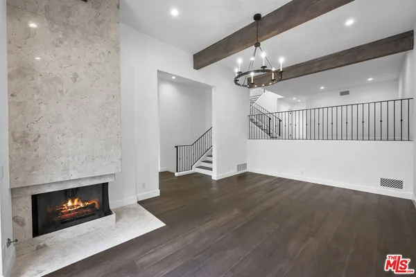 a view of an empty room with wooden floor fireplace and a chandelier