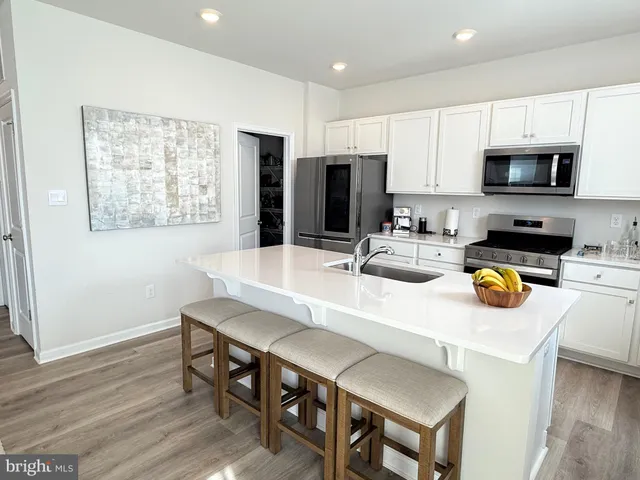 a kitchen with stainless steel appliances a dining table chairs and refrigerator